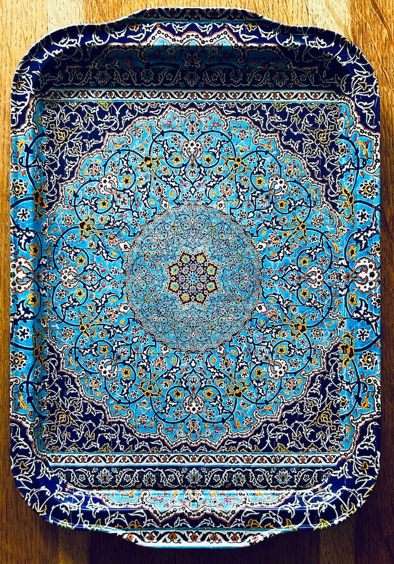 May include: A blue and gold metal serving tray with an intricate floral pattern. The tray has a raised rim and a slightly curved edge.