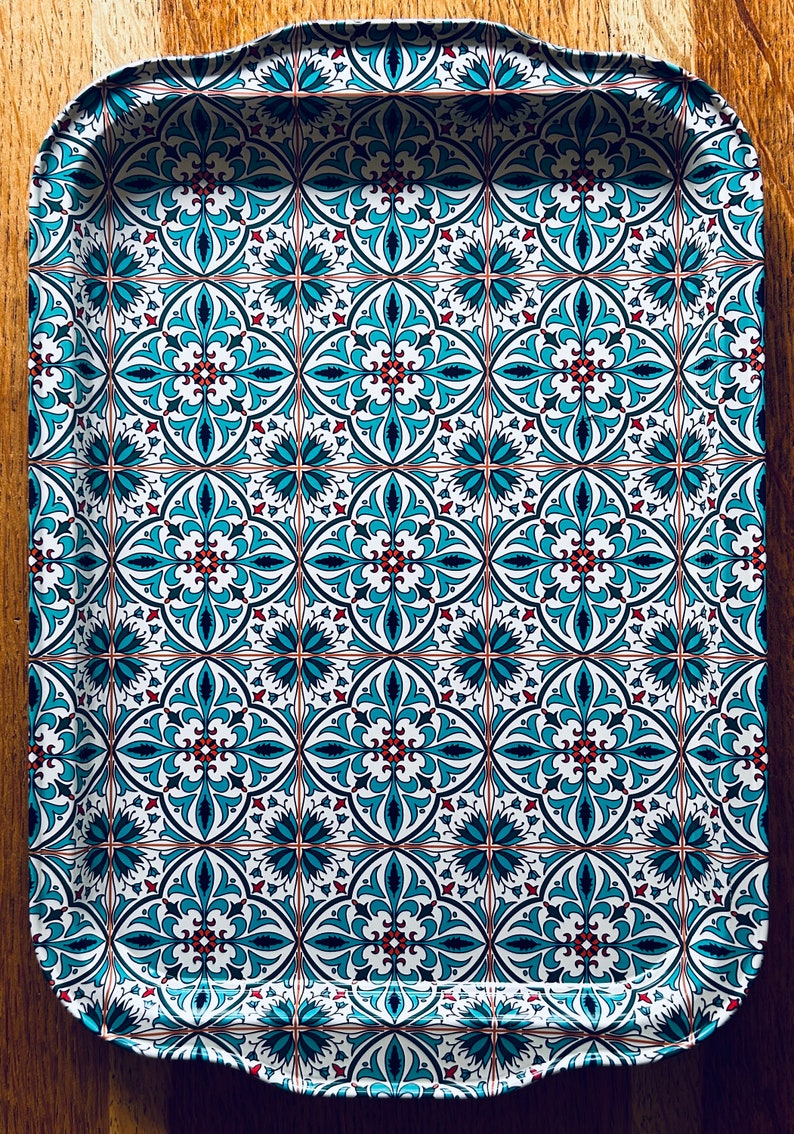 May include: A white serving tray with a blue and red geometric pattern. The tray has a scalloped edge.