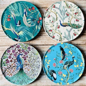 May include: Four round decorative plates featuring a blue, green, and white floral design with peacocks and other birds. The plates are ideal for adding a touch of elegance to any table setting.