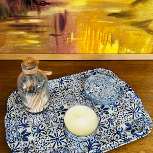 May include: A blue and white ceramic tray with a floral pattern. The tray has a candle, a jar of matches, and a small blue and white ceramic dish on it.