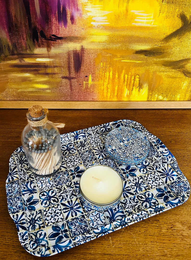 May include: A blue and white ceramic tray with a floral pattern. The tray has a candle, a jar of matches, and a small blue and white ceramic dish on it.