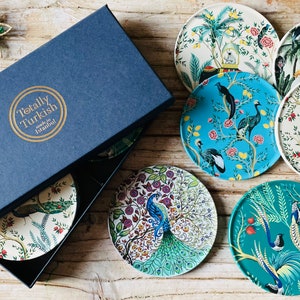 May include: A set of eight colourful coasters featuring floral and bird designs. The coasters are made in Istanbul, Turkey and are packaged in a blue box with the words "Totally Turkish" printed on the top.