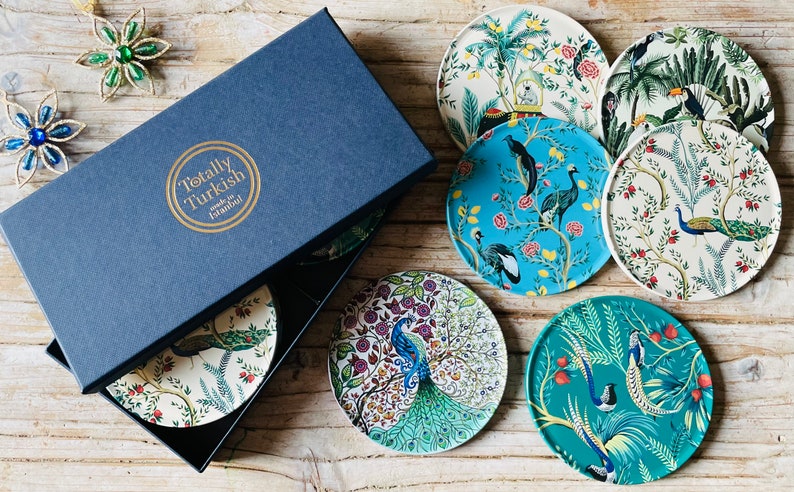 May include: A set of eight colourful coasters featuring floral and bird designs. The coasters are made in Istanbul, Turkey and are packaged in a blue box with the words "Totally Turkish" printed on the top.