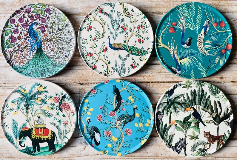 May include: Six round, white ceramic plates with colourful, intricate designs featuring peacocks, birds, and tropical plants. The plates are perfect for serving snacks, appetizers, or desserts.