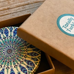 May include: A round coaster with a blue, green, and white mandala design. The coaster is in a brown cardboard box with a sticker that says "Totally Turkish made in Istanbul".