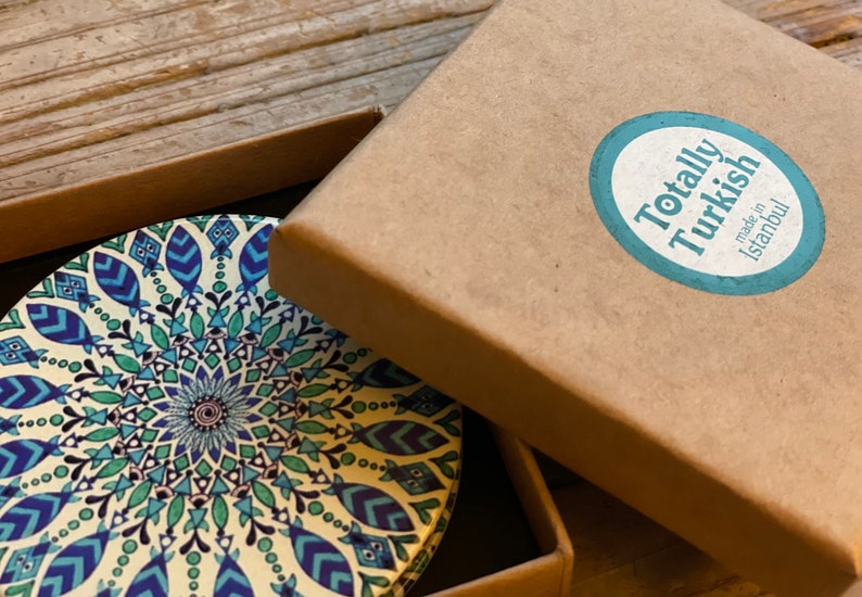May include: A round coaster with a blue, green, and white mandala design. The coaster is in a brown cardboard box with a sticker that says "Totally Turkish made in Istanbul".