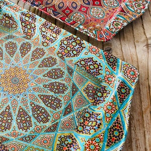 Puede incluir: Dos bandejas decorativas rectangulares con intrincados patrones geométricos. Una bandeja presenta un diseño vibrante en rojo, naranja y azul, mientras que la otra muestra un mosaico turquesa, amarillo y negro. Las bandejas parecen ser de material brillante.