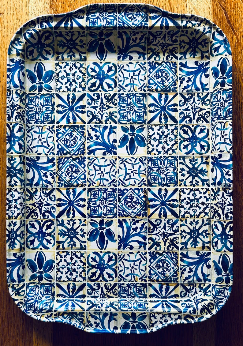 May include: A blue and white ceramic tray with a decorative tile pattern. The tray has a scalloped edge and is perfect for serving snacks or drinks.