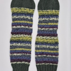 May include: A pair of knitted leg warmers. The leg warmers are primarily dark green at the top and bottom, with a striped pattern of blue, purple, yellow, and white in the middle. The knitted texture is visible.