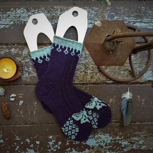 May include: A pair of purple and teal socks with a floral pattern. The socks are knitted and have a unique design.