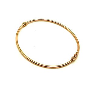 Peut inclure: Un bracelet jonc en or rose poli doté d'un anneau circulaire fin et lisse. Le bracelet comprend un petit mécanisme de fermoir intégré sur un côté avec un détail décoratif subtil en forme de nœud au niveau de la fermeture.