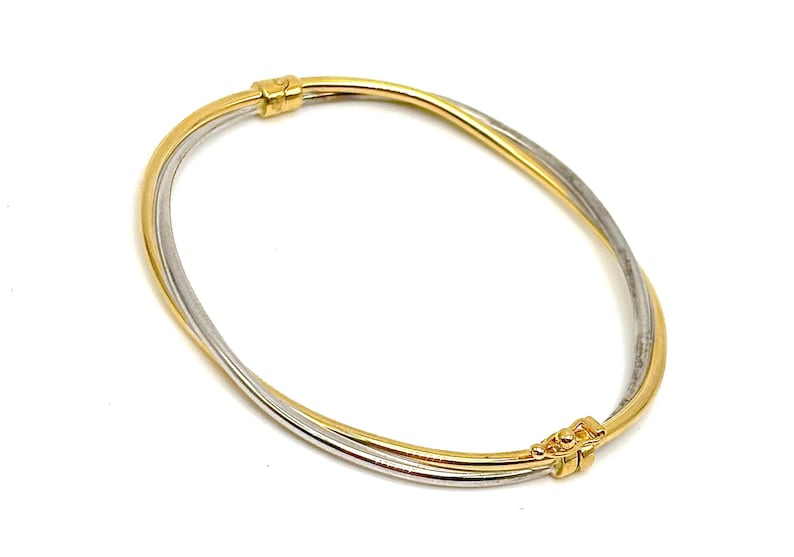 Pode incluir: Um bracelete de ouro e prata com um design tran&ccedil;ado. O bracelete &eacute; feito de duas bandas de metal entrela&ccedil;adas.