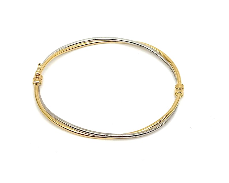 May include: A gold and silver bangle bracelet with a twisted design. The bracelet is made of two bands of metal that are intertwined.