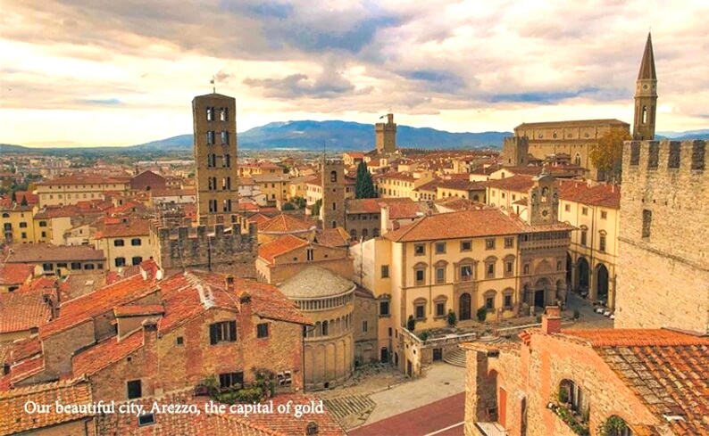 K&ouml;nnte beinhalten: Panoramablick auf Arezzo, Italien, eine historische Stadt mit Terrakotta-D&auml;chern, hohen T&uuml;rmen und einem gro&szlig;en, offenen Platz. Die Stadt ist von sanften H&uuml;geln und einem bew&ouml;lkten Himmel umgeben.