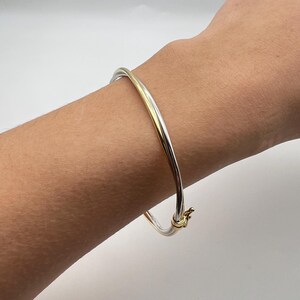 May include: A silver and gold bangle bracelet with a hinged clasp.