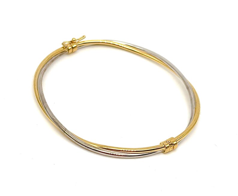 May include: A gold and silver bangle bracelet with a twisted design. The bracelet has a hinged clasp.