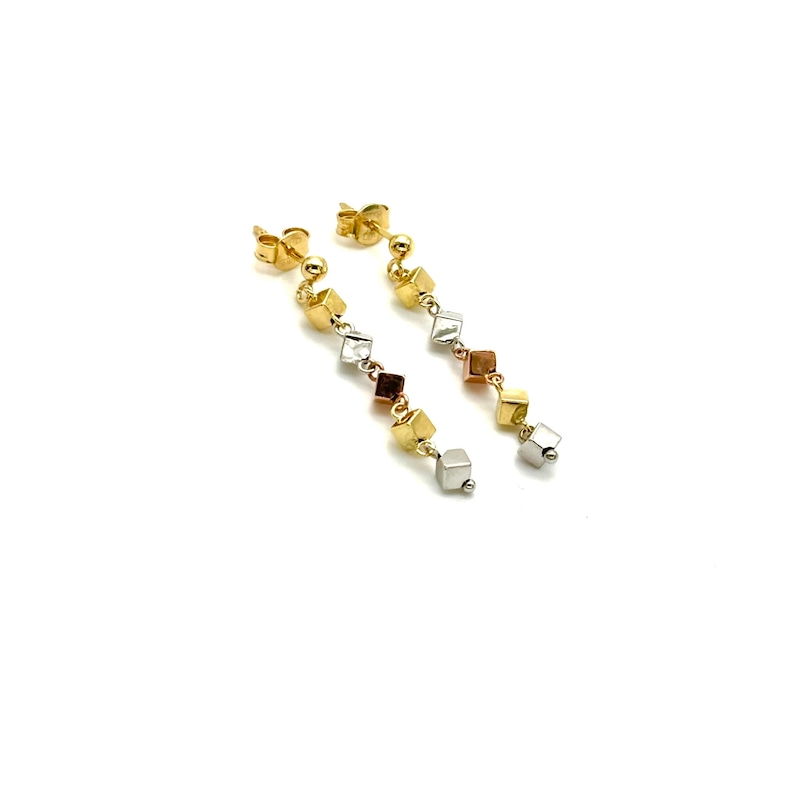Op de afbeelding: Een paar lange gouden oorbellen met een hangende ketting van kleine, vierkante kralen. De kralen zijn in drie verschillende kleuren: goud, zilver en ros&eacute; goud.