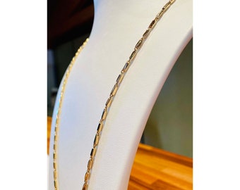 Op de afbeelding: Een gouden ketting met een delicaat, box-ketting ontwerp. De ketting is gemaakt van kleine, rechthoekige schakels.