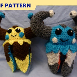 May include: Two crocheted plush toys, one yellow with brown and blue accents, and one blue with gray and white accents. Both toys have large eyes and a smiling expression. The toys are posed with their arms raised in the air.  PDF PATTERN.