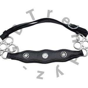 Op de afbeelding: Zwart lederen paardenbit met zilveren ringen en bloemvormige accenten.