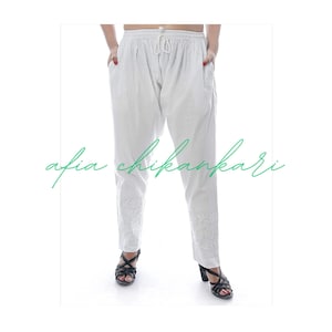 May include: White cotton pants with embroidered details. The pants have a drawstring waistband and are a loose, comfortable fit.