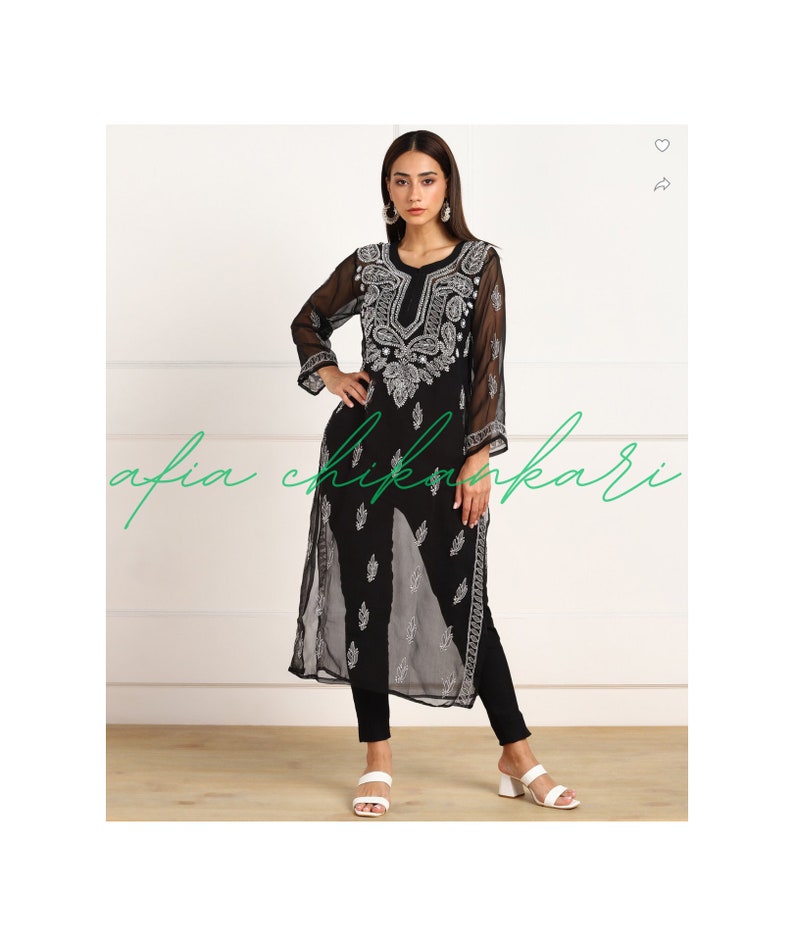May include: A black sheer tunic with silver embroidery featuring a paisley design. The tunic has a V-neckline and long sleeves. The model is wearing black trousers and white sandals.