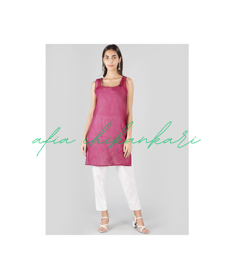 Puede incluir: Una t&uacute;nica larga sin mangas de color magenta con un escote cuadrado. La modelo lleva pantalones blancos y sandalias blancas.