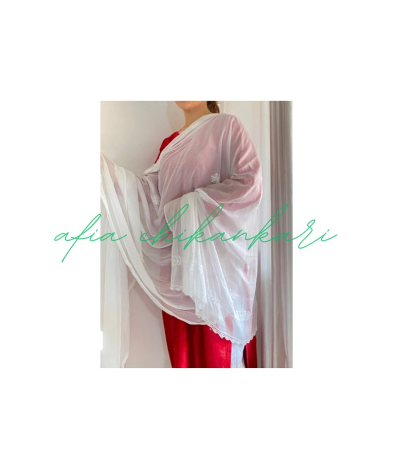 May include: A white sheer dupatta with delicate white embroidery. The dupatta is draped over a person wearing a red dress. The text "afia chikankari" is visible in the lower left corner of the image.