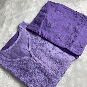 May include: A purple embroidered kurta and matching pants set. The kurta has a V-neck and is decorated with intricate floral embroidery. The pants are plain and have a straight leg.