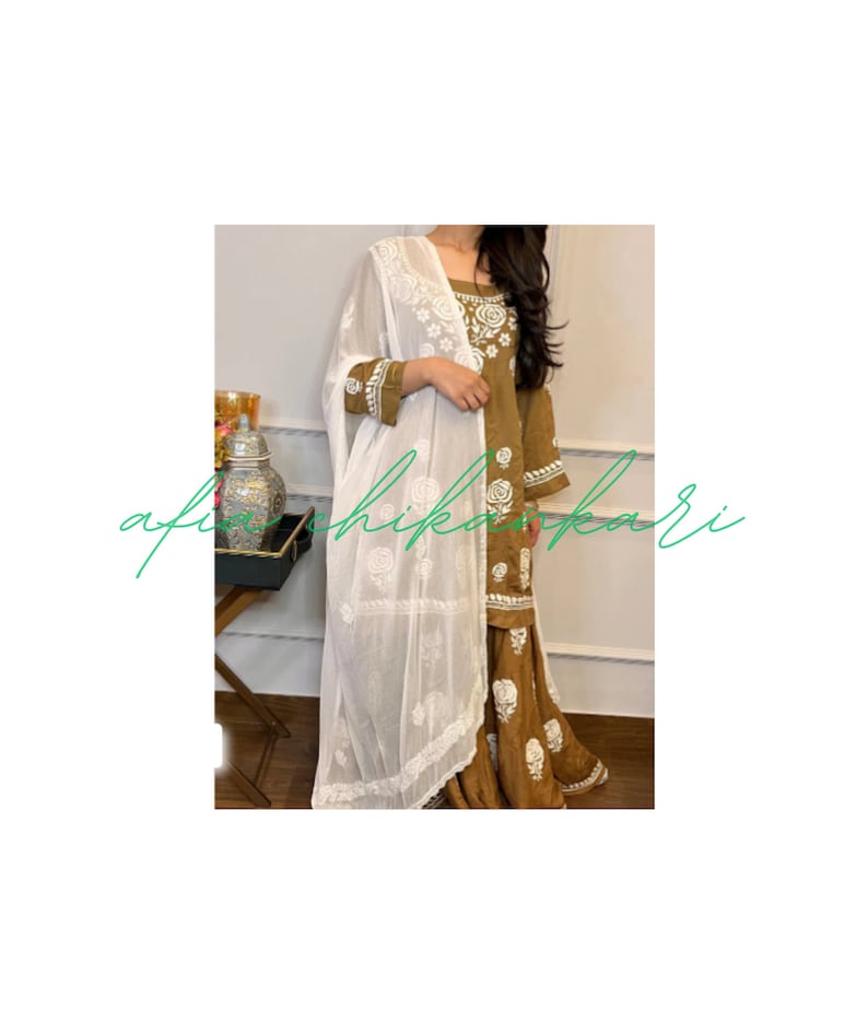 May include: A brown and white embroidered dress with a white dupatta. The dress has a floral pattern and the dupatta is sheer.