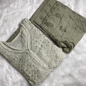 May include: A two-piece set of sage green cotton garments, both featuring intricate floral embroidery. The top has a V-neck, while the bottom is a pair of trousers.