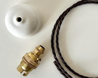 May include: A white ceramic ceiling rose, a brass light bulb socket with a side switch, and a length of brown twisted fabric-covered electrical cord. The components are arranged separately to show the parts of a pendant light fixture assembly.