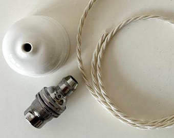 May include: A white ceramic ceiling rose, a metallic silver light bulb socket, and a length of twisted white fabric-covered electrical cord. The components are arranged separately, showing the individual parts of a pendant light fixture assembly.