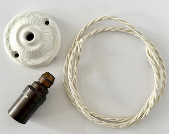 May include: A collection of vintage-style lighting components, including a white ceramic ceiling canopy with a floral design, a dark brown lamp holder, and a cream-colored twisted fabric cord.