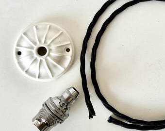May include: A white circular ceiling canopy with a radial ribbed pattern, a silver metal light bulb socket, and a long black fabric-covered twisted electrical cord. The components are arranged separately to show the parts of a light fixture.