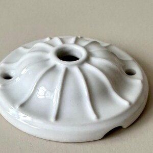 May include: White ceramic ceiling rose with a decorative fluted design and three holes.