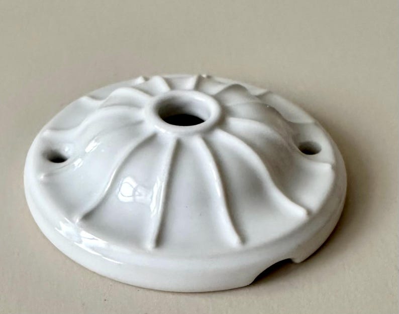 May include: White ceramic ceiling rose with a decorative fluted design and three holes.