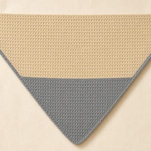 Peut inclure: Un châle triangulaire au crochet présentant un design bicolore avec une grande section de fil beige clair sur la moitié supérieure et une section plus petite de fil gris foncé sur la moitié inférieure, bordé d'une bordure au crochet gris foncé.