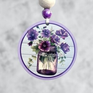 May include: Purple flowers in a glass jar with a white wooden background. The jar has the word "remarkable" written on it. The image is a round, purple-bordered design.