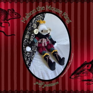 May include: A crocheted doll of Mabon the Mouse King, with a white face, yellow crown, and red and black outfit. The image is set against a red striped background with illustrations of rats and the text "Mabon the Mouse King" and "pdf pattern".