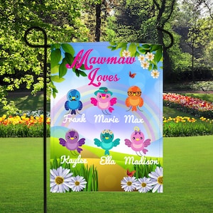 May include: A colorful garden flag with a blue sky background and a rainbow. The text "Mawmaw Loves" is at the top of the flag. There are six cartoon birds with names below each bird: Frank, Marie, Max, Kaylee, Ella, and Madison.