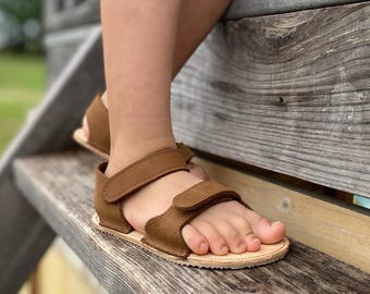 Sandália infantil de couro feita à mão, inspirada no estilo descalço.