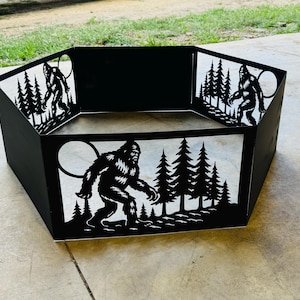 Puede incluir: Hoguera de metal negro con diseños recortados de Bigfoot y escenas de bosque. La hoguera hexagonal presenta siluetas de Bigfoot, árboles y una luna llena. La hoguera está diseñada para uso en exteriores.