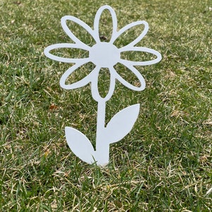 May include: White metal daisy flower garden stake with a simple design. The stake is inserted into the ground and features a stylized flower with a stem and leaves.
