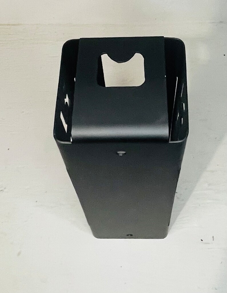 May include: Black metal wall mounted holder with a rectangular shape and a cut-out for a roll of paper towels.