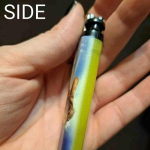May include: A yellow and blue lighter with a cat image on the side. The lighter has a black top and a silver metal body.