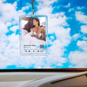 May include: A clear plastic keychain with a photo of a woman in a white dress. The keychain has a music player design with the text "You Are Not Alone" and "Michael Jackson".