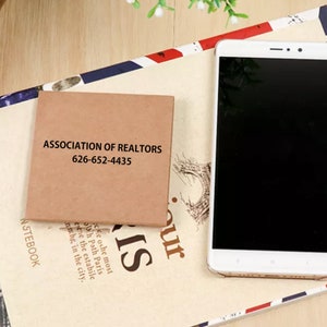 May include: A brown paper notecard with the text "ASSOCIATION OF REALTORS 626-652-4435" printed in black.