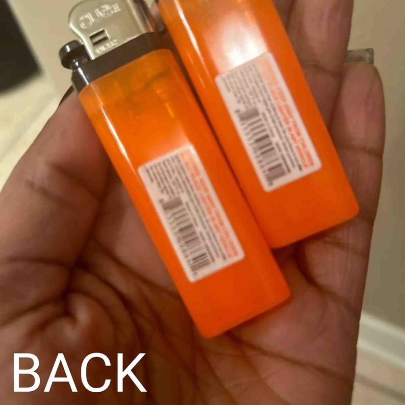 May include: Two orange lighters with black tops and silver accents. The lighters have a white label with black text and a barcode.