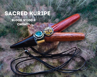 May include: A wooden kuripe, a traditional ceremonial pipe, with a black and red wood design. It has a green and gold gemstone on the end and a black cord for hanging. The text "SACRED KURIPE" and "BLOOD WOOD & CHONTA" is visible in the image.